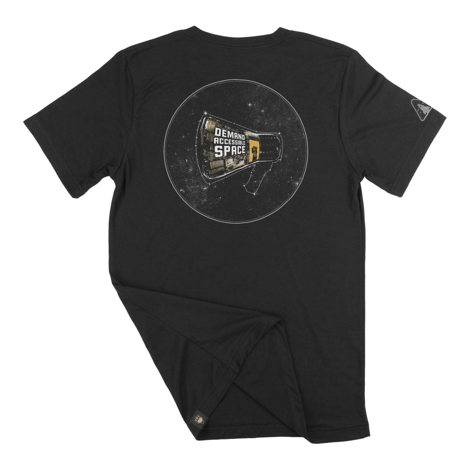 The back of black t-shirt featuring the “Rise Up" design. The design features a space capsule modeled after the Mercury capsule, depicted in high contrast black and white with gold details, enclosed in a white circle. Wrapping the side of the capsule are the words, “Demand Accessible Space” above a small window. Next to the text and window is a gold banner with a black fist, a gold infinity symbol on the arm of the fist. The banner is a “Black Disabled Lives Matter” graphic created by the same artist. The capsule floats in front of a field of stars, and is outlined by a constellation in the shape of a megaphone.